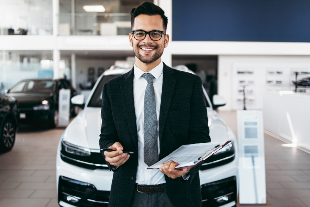 Car dealer standing and posing in showroom